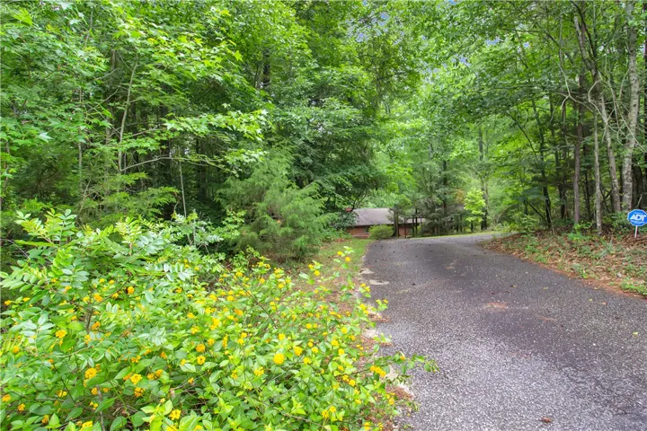 A secluded retreat nestled in a verdant, wooded landscape with a private driveway leading to the home.