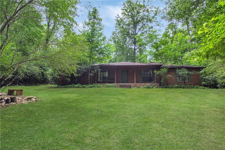 Mature trees surround this brick home with a welcoming front porch and verdant lawn.