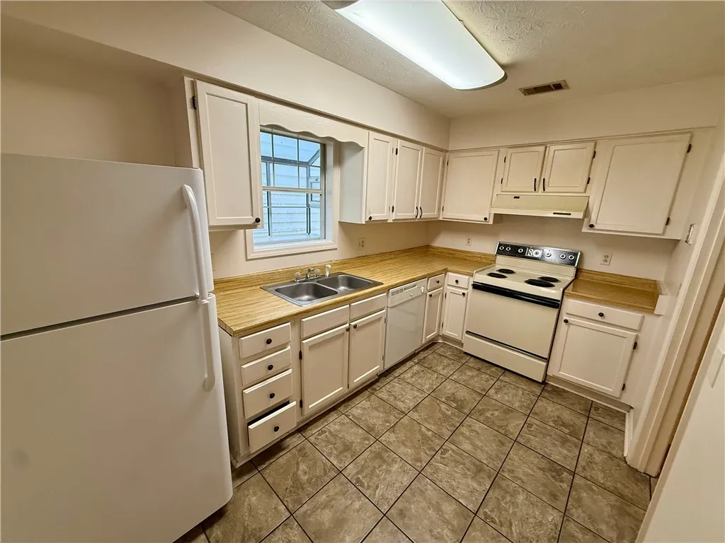 Functional kitchen with ample cabinet space, a dual sink, and durable tile flooring.