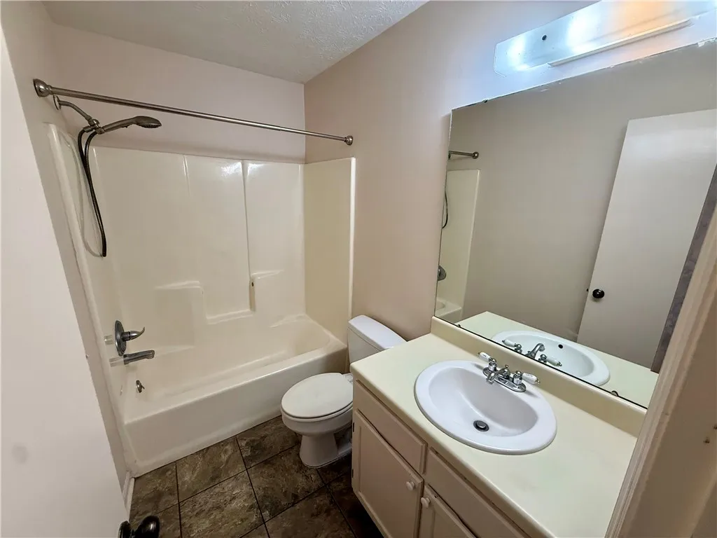 Functional bathroom features a clean tub and shower combination with a vanity sink and large mirror.