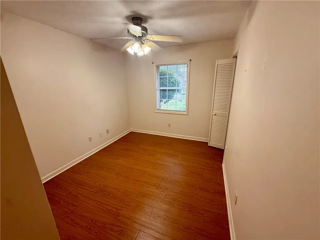 Hardwood-style flooring and a ceiling fan provide comfort in this naturally illuminated space.