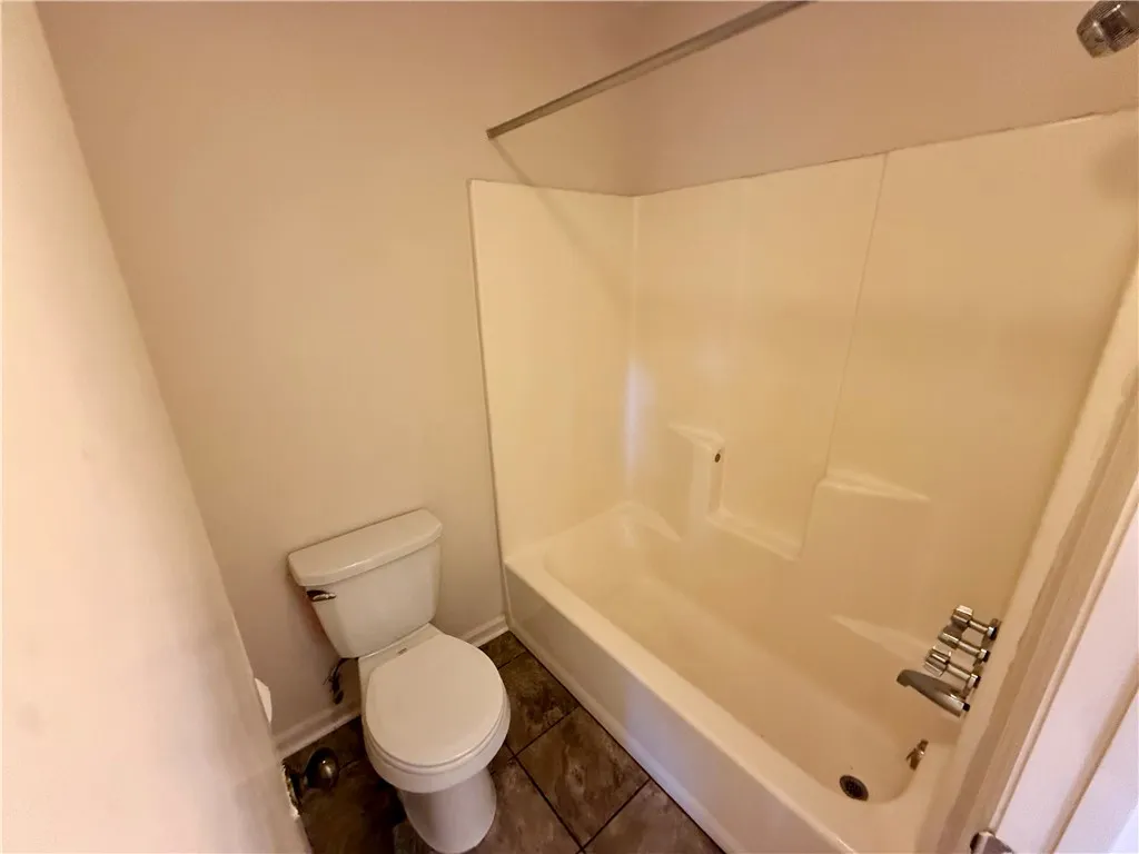 Functional bathroom featuring a shower-tub combination and tiled flooring, ready for daily use.
