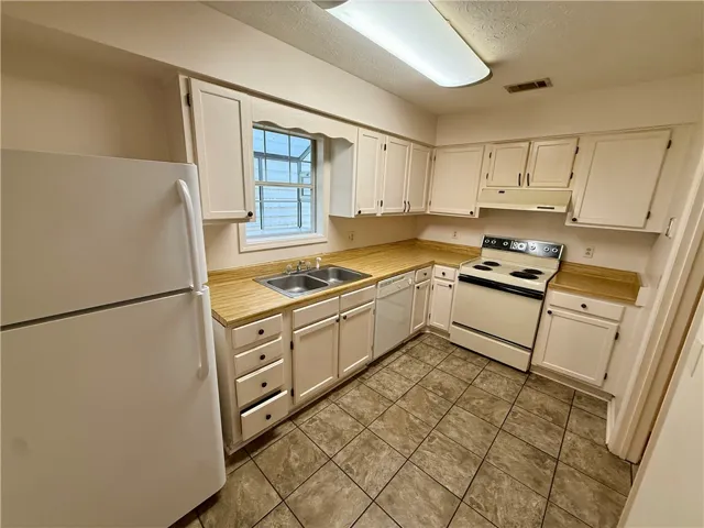 Functional kitchen with ample cabinet space, a dual sink, and durable tile flooring.