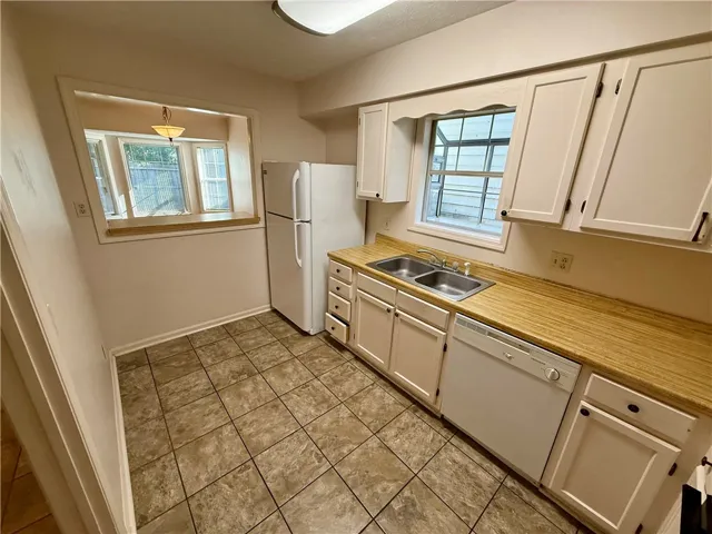 Functional kitchen with ample cabinet space, dual sinks, and pass-through window.