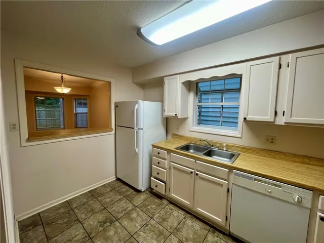 Functional kitchen with ample cabinet space, a pass-through window, and durable tiled flooring.