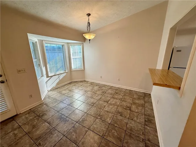 Naturally illuminated dining space, featuring durable tile flooring and vaulted ceilings.