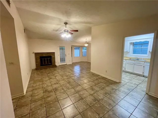A welcoming living space features a cozy brick fireplace and tiled flooring throughout.