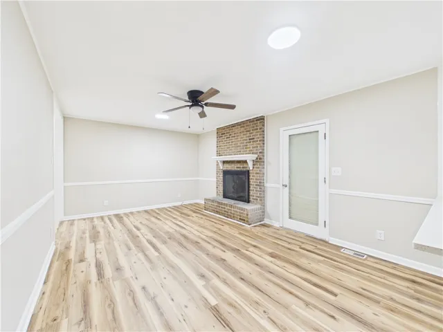 A cozy living space awaits, featuring a prominent brick fireplace and rich hardwood flooring.