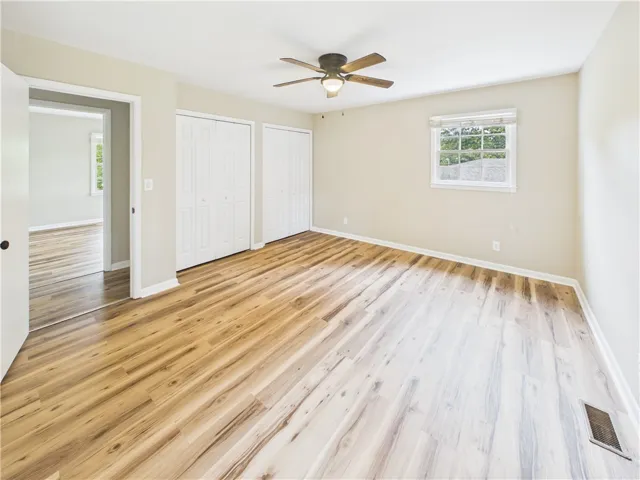 Luminous flooring and a ceiling fan enhance this adaptable and inviting bedroom space.