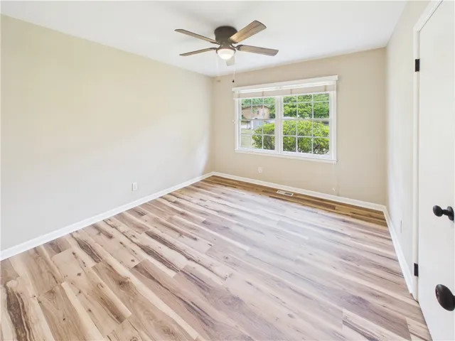 A quiet bedroom featuring elegant wood flooring and a refreshing ceiling fan.