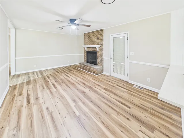 A welcoming living space features warm flooring and a classic brick fireplace.