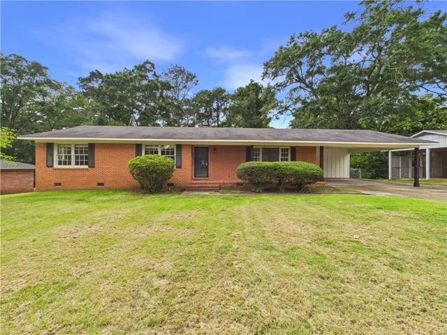 Brick facade home featuring a convenient carport and lush green surroundings.