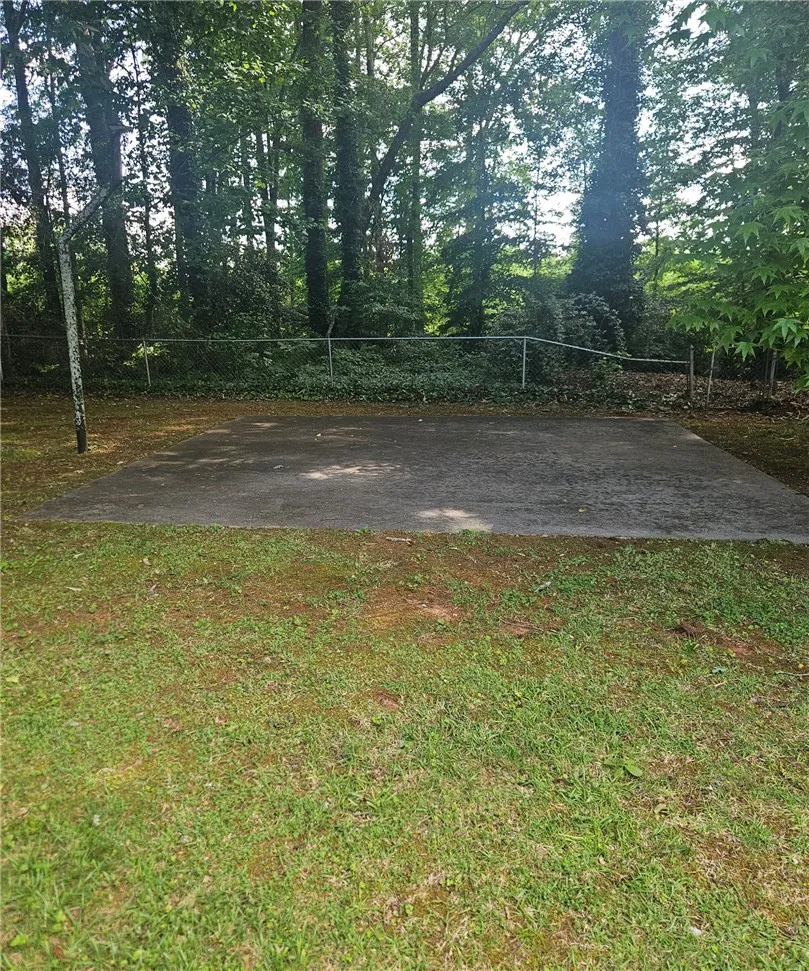 A flat concrete slab offers potential for recreation in a wooded yard.