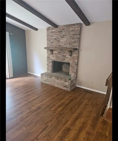 Rich wood flooring complements a grand brick fireplace with an elegant wood mantel.