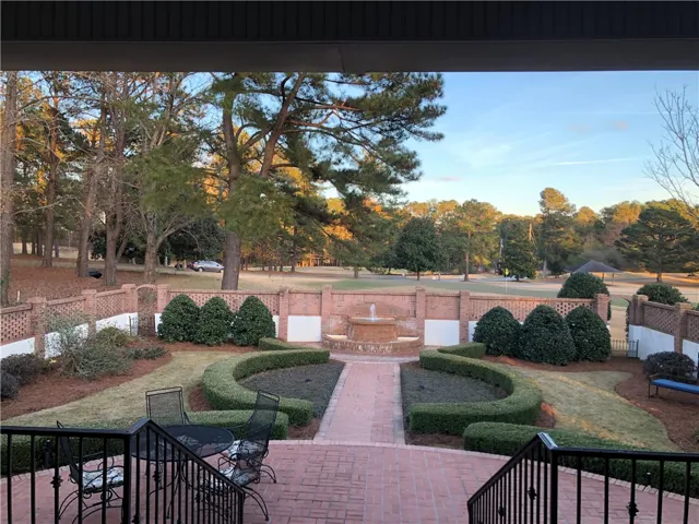 Elegant brick patio offers prime views of a meticulously manicured golf course and garden fountain.