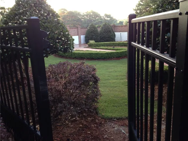 Enter a serene backyard garden, impeccably landscaped with a manicured lawn and privacy fencing.
