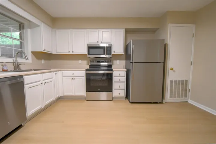 A well-equipped kitchen features pristine white cabinetry and modern stainless steel appliances.