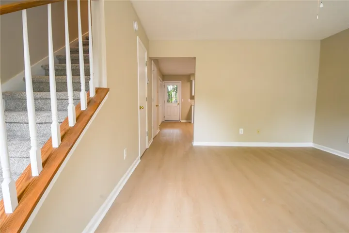 A graceful staircase with carpeted treads and natural wood accents complements the light wood flooring throughout.