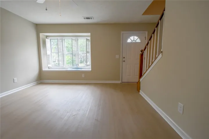 A well-lit main living space offers fresh flooring and a welcoming front entry with staircase.