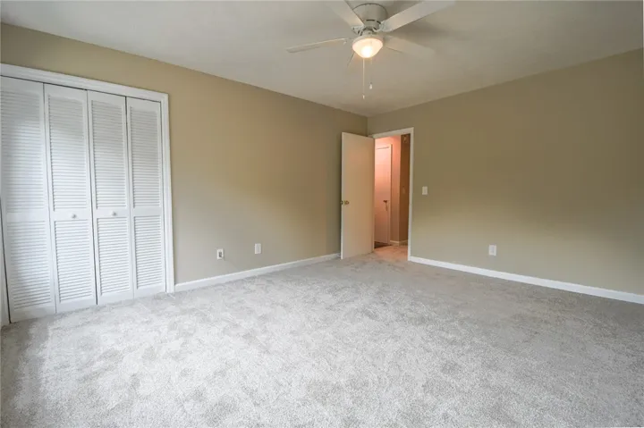 A spacious bedroom featuring plush carpeting and a convenient ceiling fan.