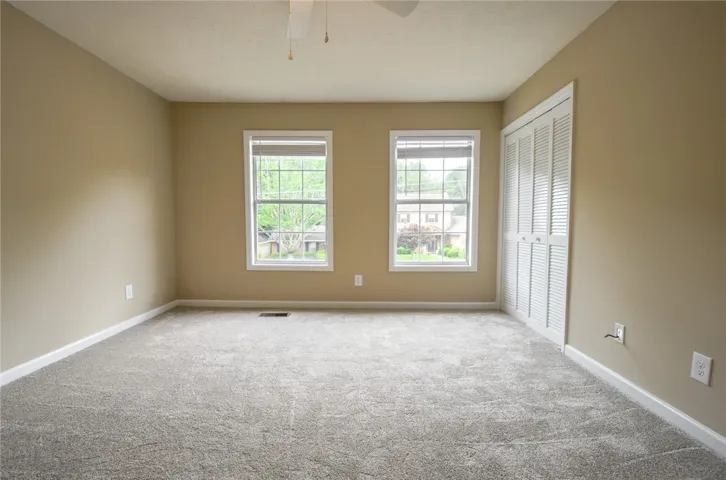 A quiet bedroom offers dual windows overlooking the neighborhood and a practical closet with louvered doors.