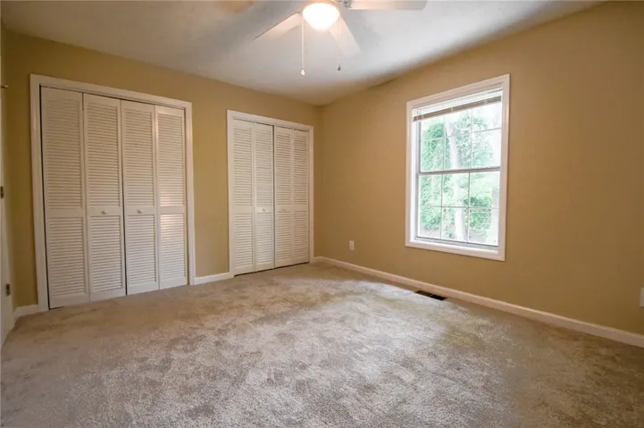 A comfortable bedroom with dual louvered closets and a broad window inviting natural light.