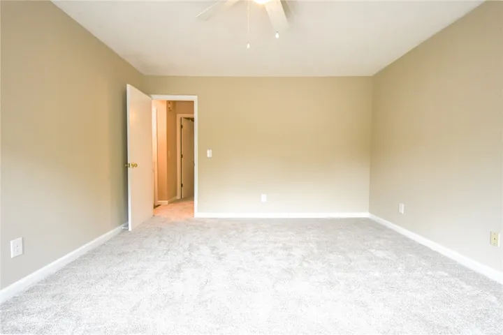 A spacious, naturally illuminated room featuring plush carpet flooring and clean, neutral walls.