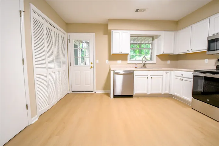 Bright, practical kitchen space with light wood flooring and crisp white cabinetry.