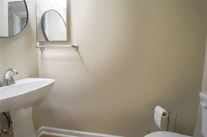 A compact and functional bathroom features a modern pedestal sink and wall-mounted mirror.