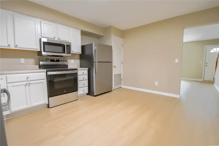 A well-equipped kitchen features light wood flooring and sleek stainless steel appliances, ready for culinary endeavors.
