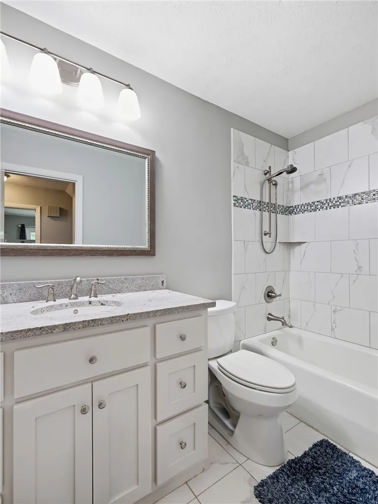 Granite counters and tiled shower create a pristine and inviting bathroom environment.
