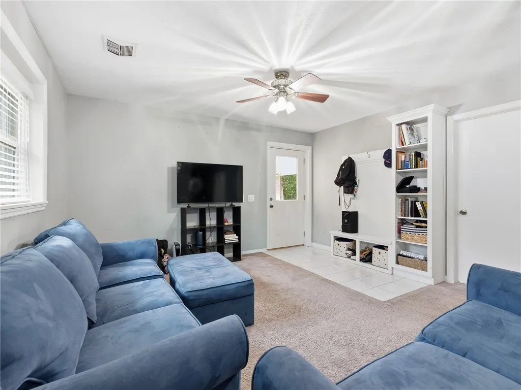 A versatile living area features carpeted floors and a ceiling fan, offering comfortable everyday living.