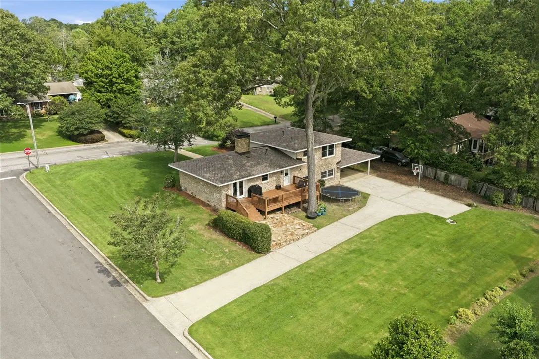 An inviting brick home with a spacious lawn and a large deck perfect for outdoor enjoyment.