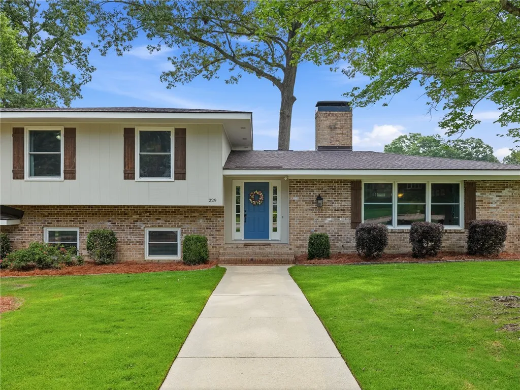 A classic brick and siding residence features a welcoming blue front door and neatly manicured landscaping.