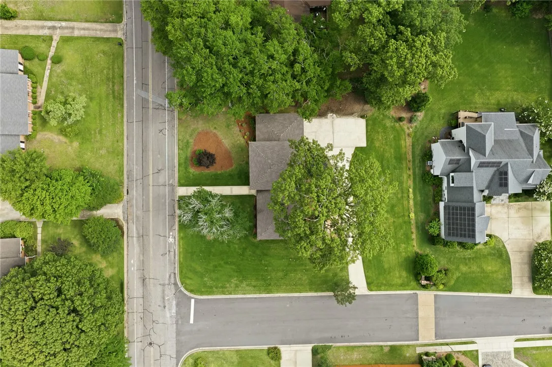 An aerial perspective reveals a well-maintained property with mature trees and a neatly paved driveway.