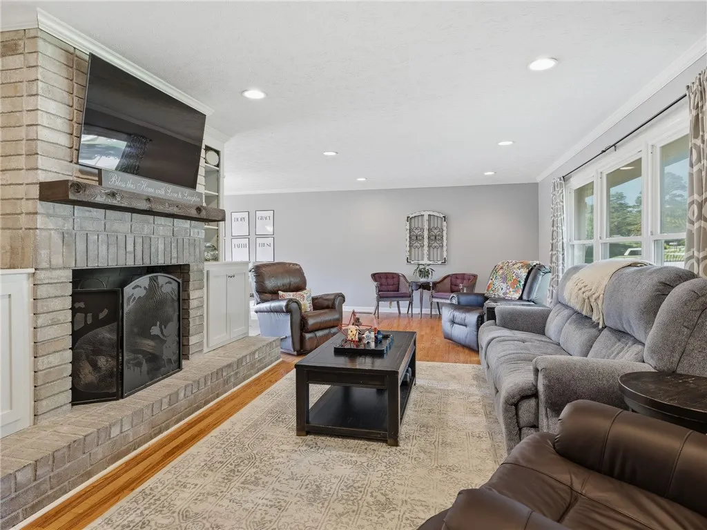A comforting living area boasts a robust brick fireplace and ample natural illumination from broad windows.