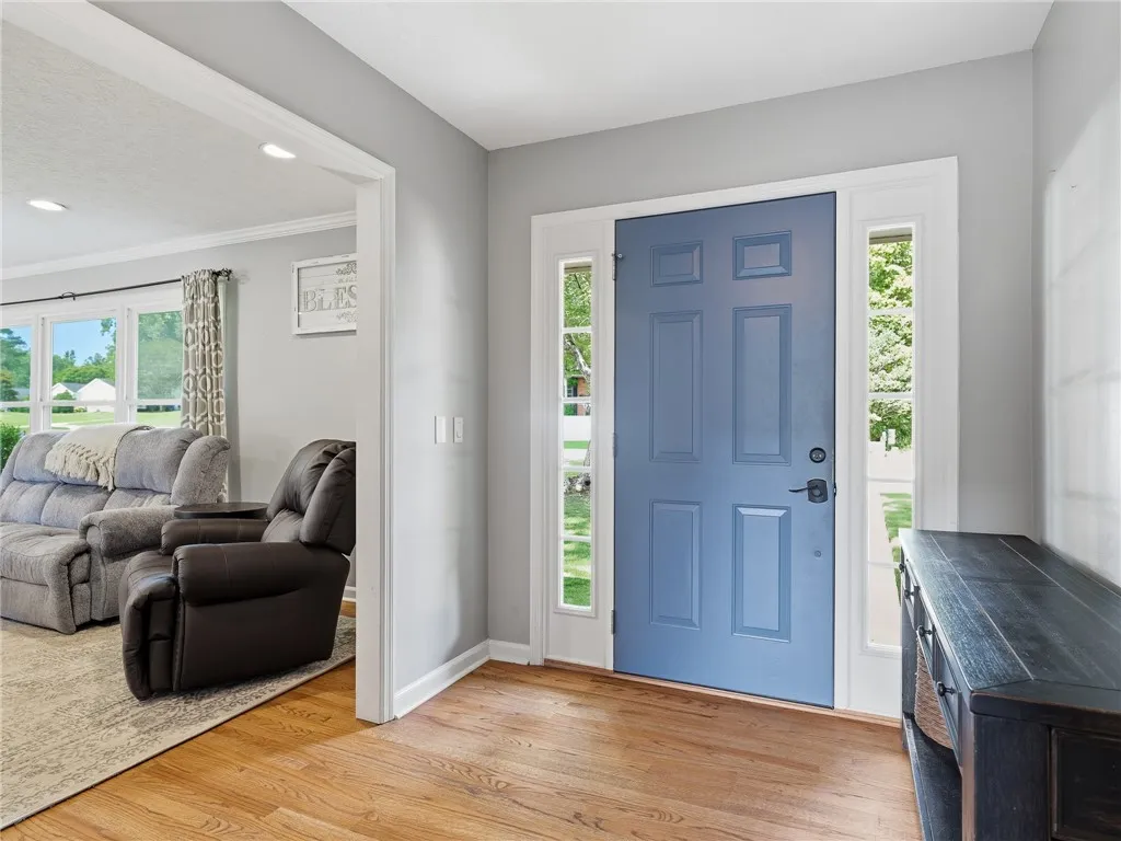 A welcoming entry, framed by sidelights, features a vibrant blue front door opening to warm hardwood flooring.