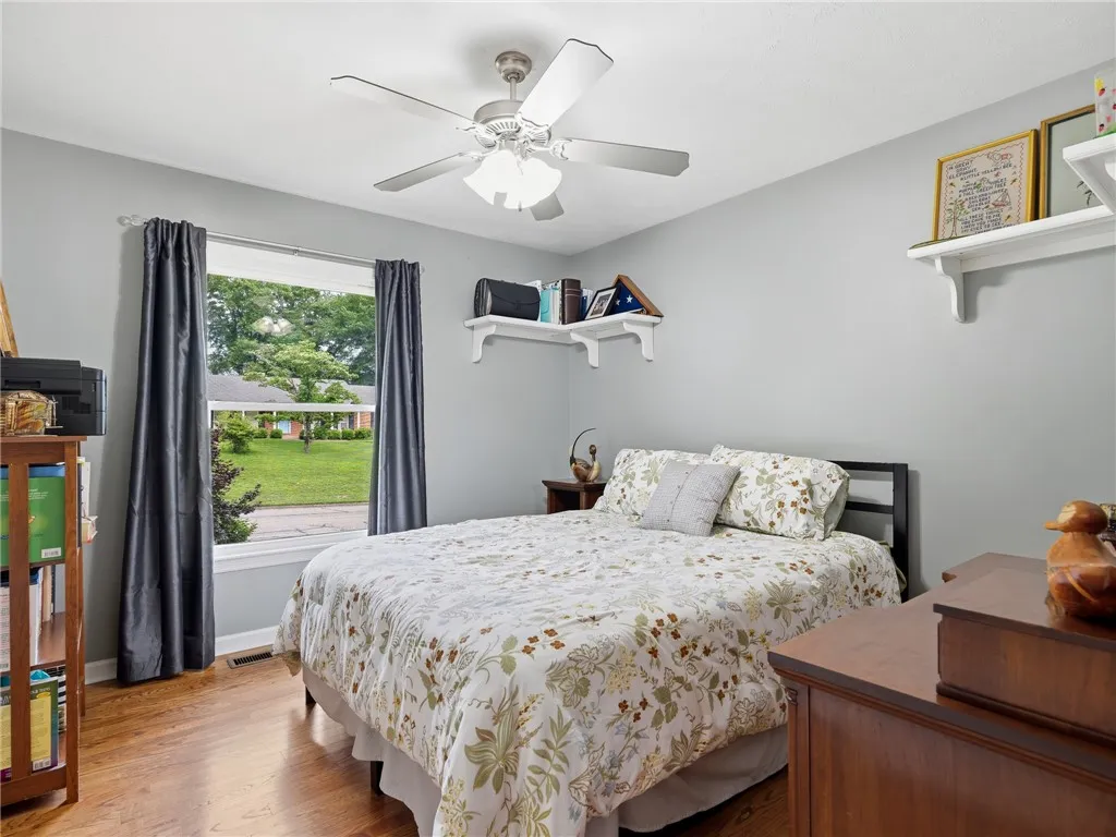 Well-lit sleeping quarters with rich hardwood flooring and a refreshing ceiling fan.