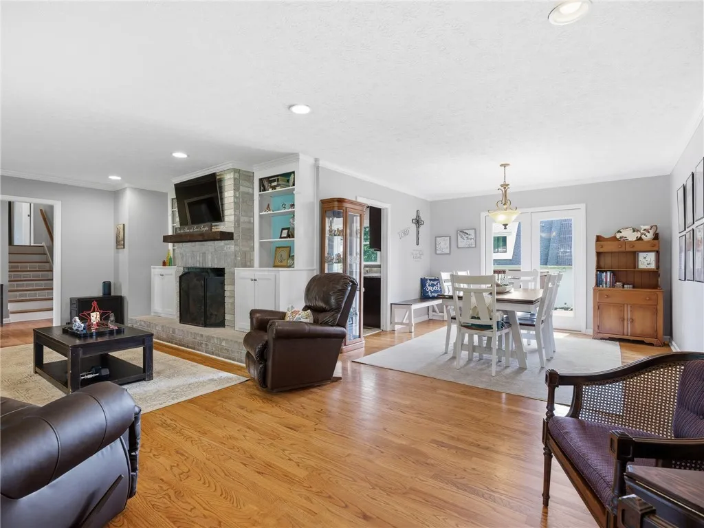 Hardwood floors flow through the open-concept living area, featuring a brick fireplace and adjacent dining space with outdoor access.