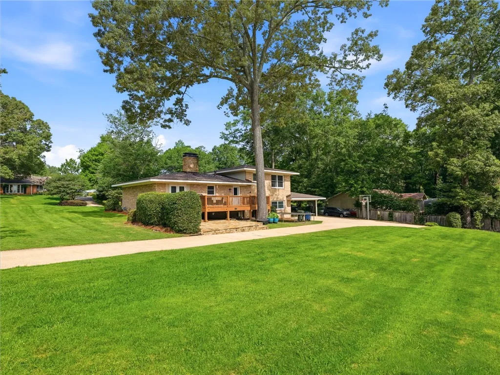 Mature trees and lush lawns frame this brick residence with a welcoming outdoor deck and ample driveway space.