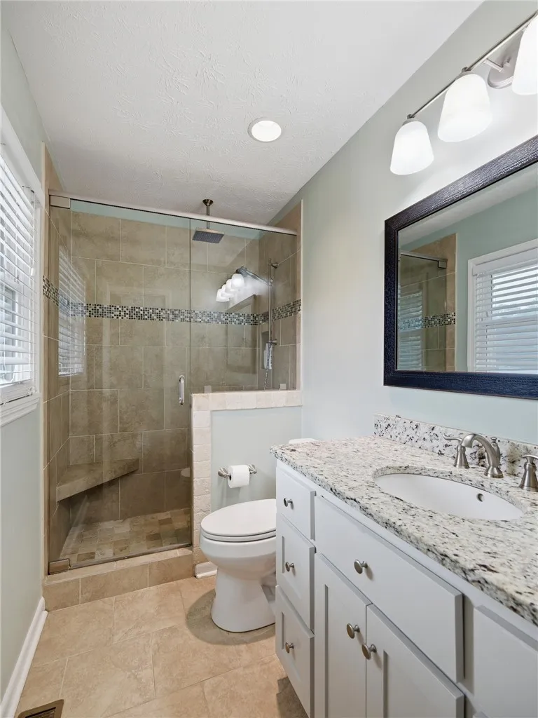 A clean, modern bathroom offers a spacious walk-in shower and elegant vanity.