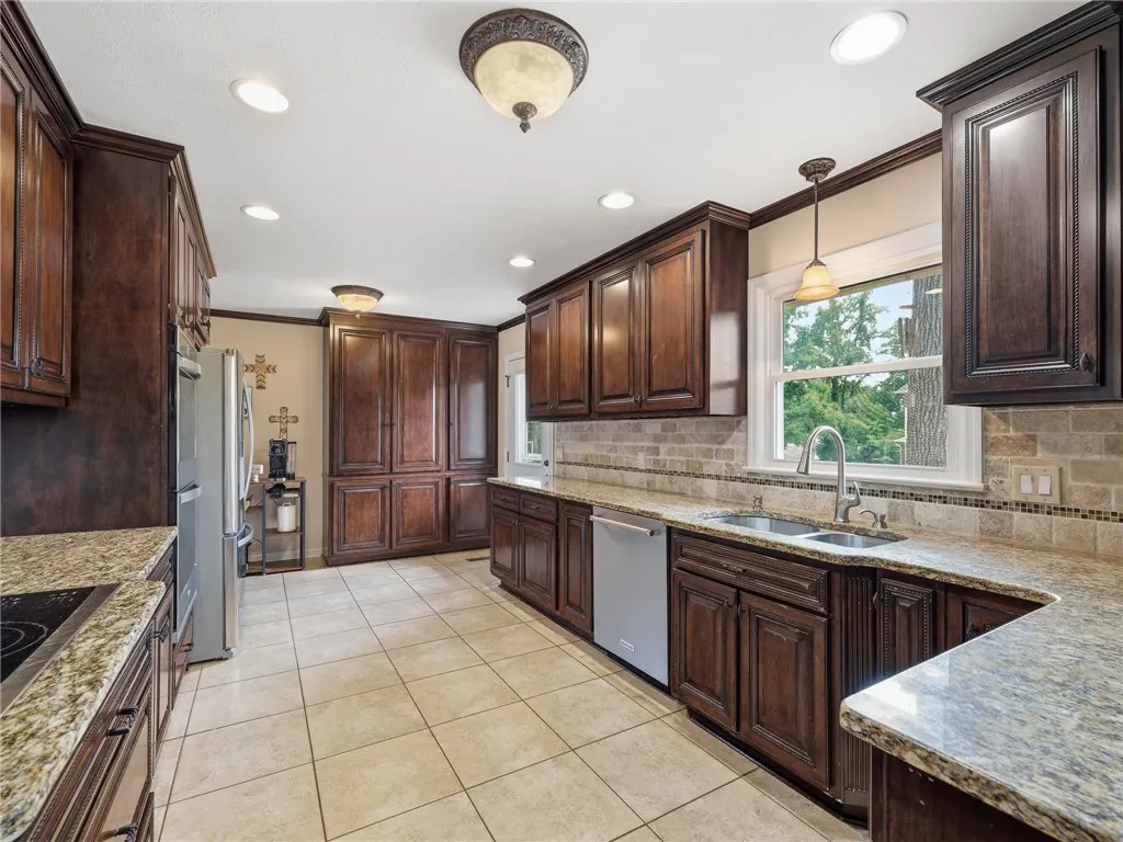 Warm wood cabinetry and durable granite counters outfit this spacious, well-appointed cooking area.