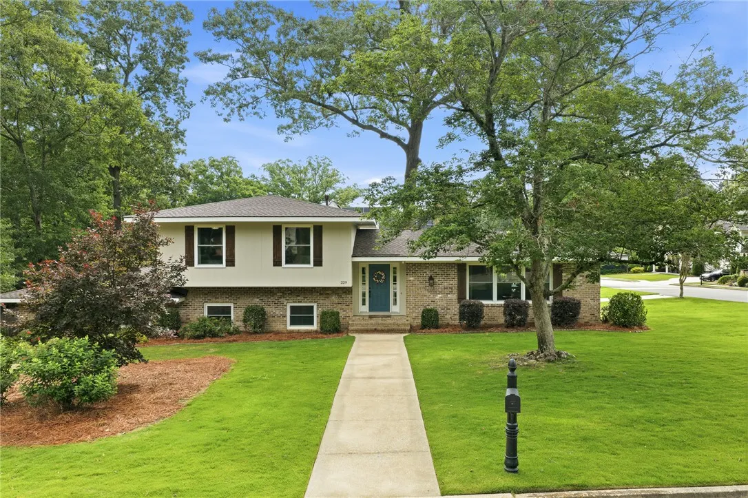 A classic brick and siding home with a welcoming front path and verdant landscaping.