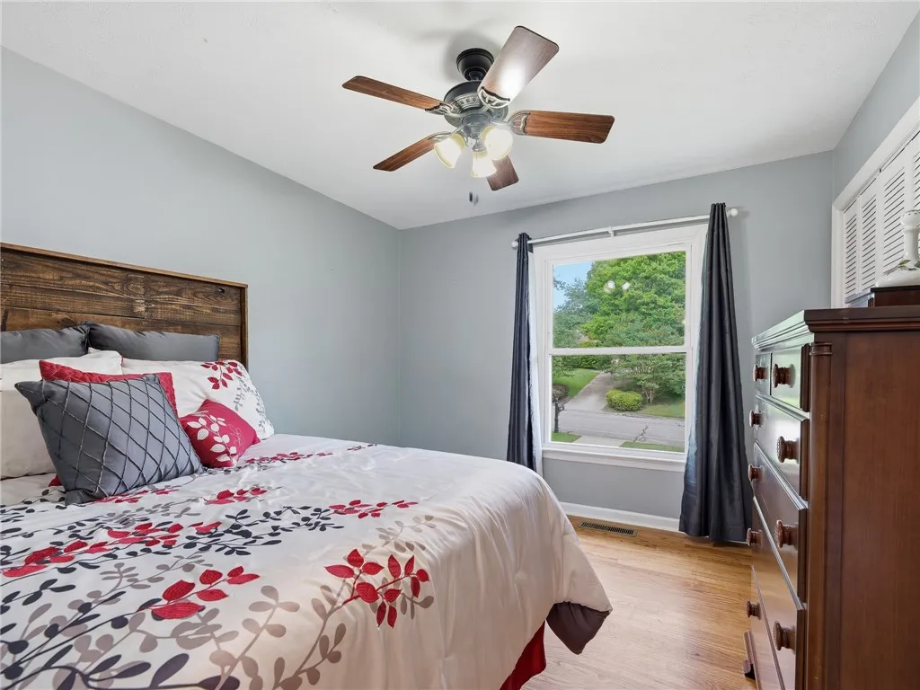 Comfortable sleeping quarters feature a warm wood headboard, hardwood floors, and a bright window view.