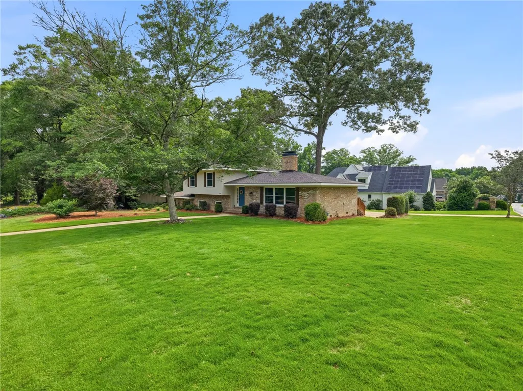 A classic facade with a welcoming blue door fronts a verdant lawn and mature shade trees.