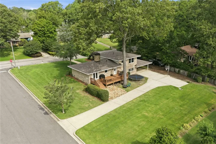 An inviting brick home with a spacious lawn and a large deck perfect for outdoor enjoyment.