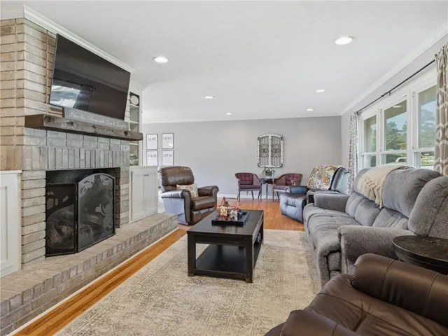 A comforting living area boasts a robust brick fireplace and ample natural illumination from broad windows.
