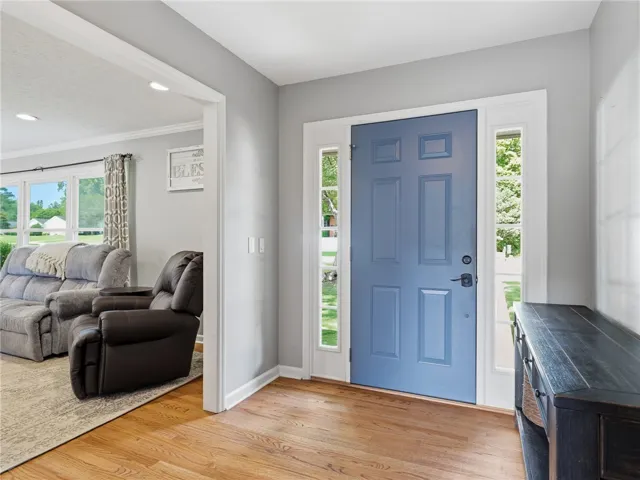 A welcoming entry, framed by sidelights, features a vibrant blue front door opening to warm hardwood flooring.