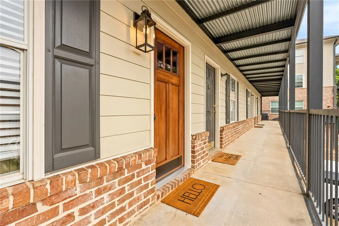 A welcoming wooden entry door with transom window detail fronts this covered walkway, accented by brick and horizontal siding.