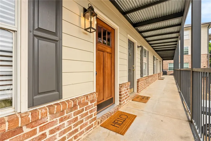 A welcoming wooden entry door with transom window detail fronts this covered walkway, accented by brick and horizontal siding.